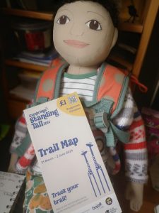 A doll holding a charity trail map.